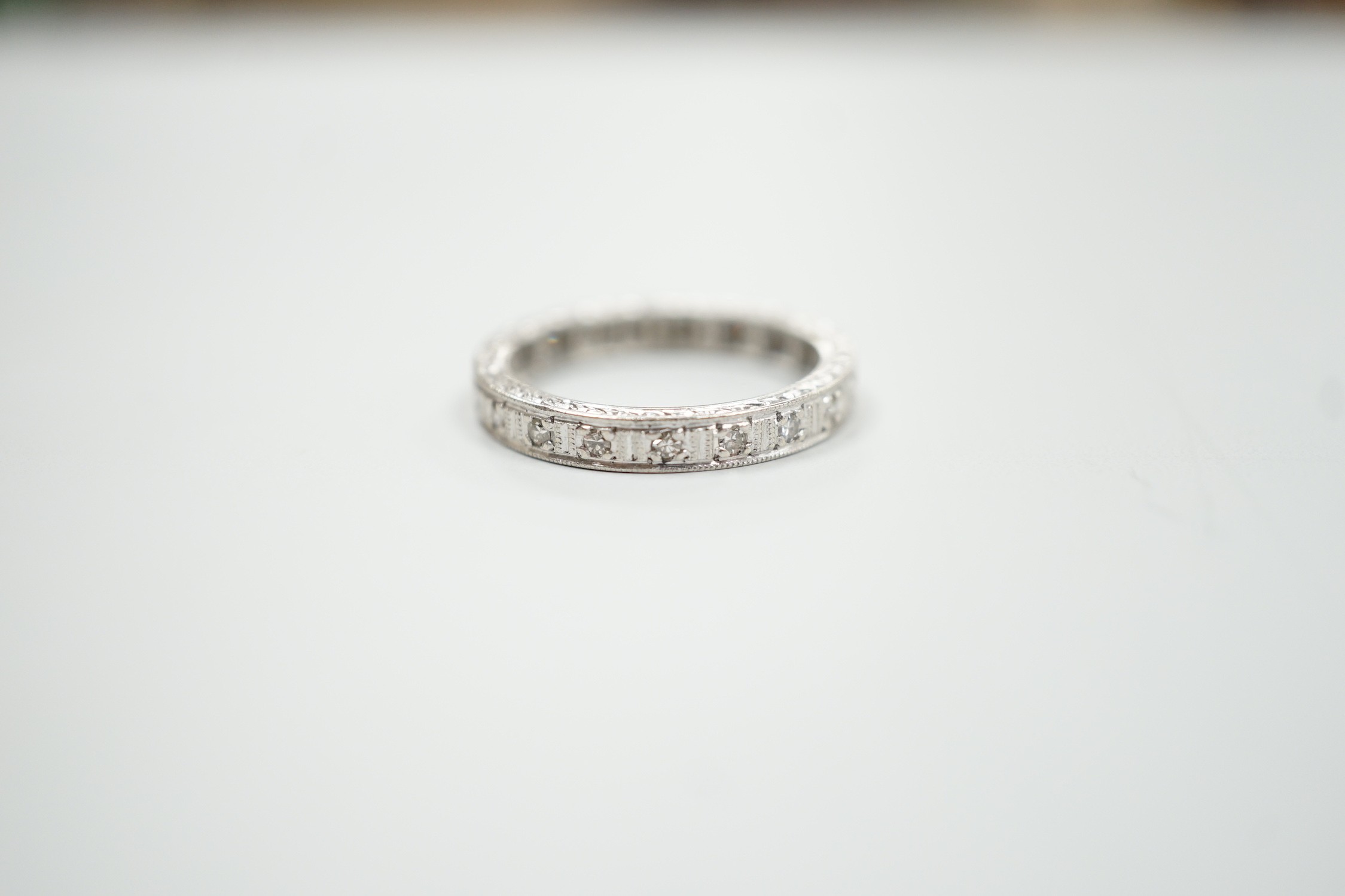 A white metal, stamped plat and diamond chip set full eternity ring, size K, gross weight 3.7 grams.